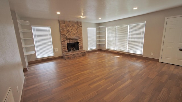 1203 Brook Grove Dr, Katy, TX 77450 - unfurnished living room featuring wood finished floors, built in features, baseboards, a large fireplace, and recessed lighting