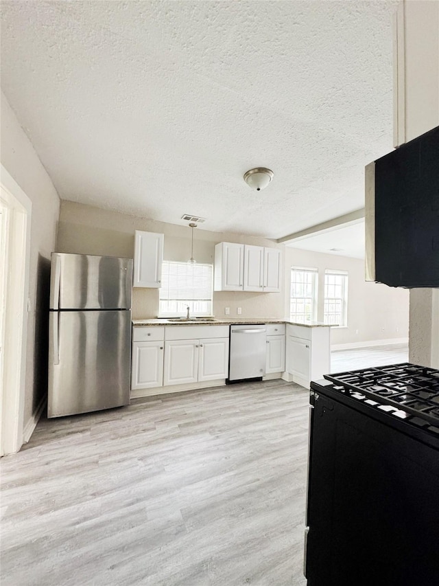 609 Martin Luther King Jr Blvd, Corsicana, TX 75110 - kitchen with appliances with stainless steel finishes, a sink, light wood-style floors, a textured ceiling, and healthy amount of natural light