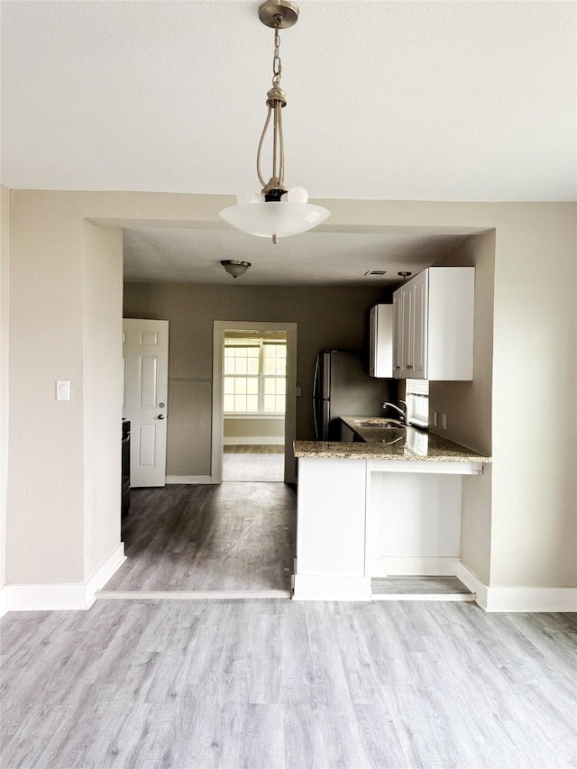 609 Martin Luther King Jr Blvd, Corsicana, TX 75110 - kitchen with baseboards, light wood-style floors, light stone counters, and freestanding refrigerator