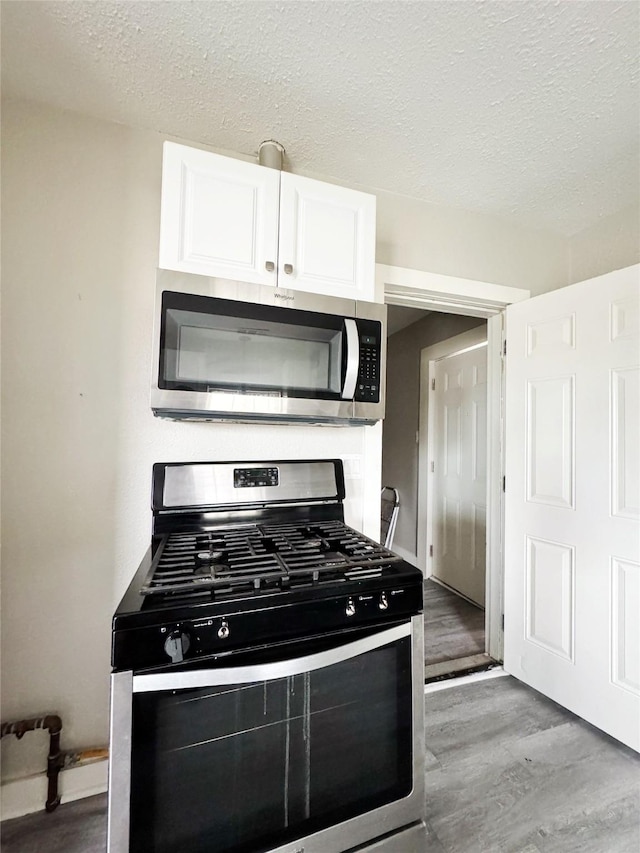 609 Martin Luther King Jr Blvd, Corsicana, TX 75110 - kitchen featuring appliances with stainless steel finishes, light wood-style flooring, white cabinetry, and a textured ceiling