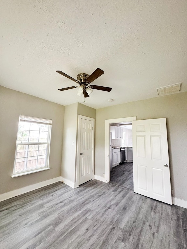 609 Martin Luther King Jr Blvd, Corsicana, TX 75110 - unfurnished bedroom featuring a textured ceiling, wood finished floors, baseboards, connected bathroom, and ceiling fan