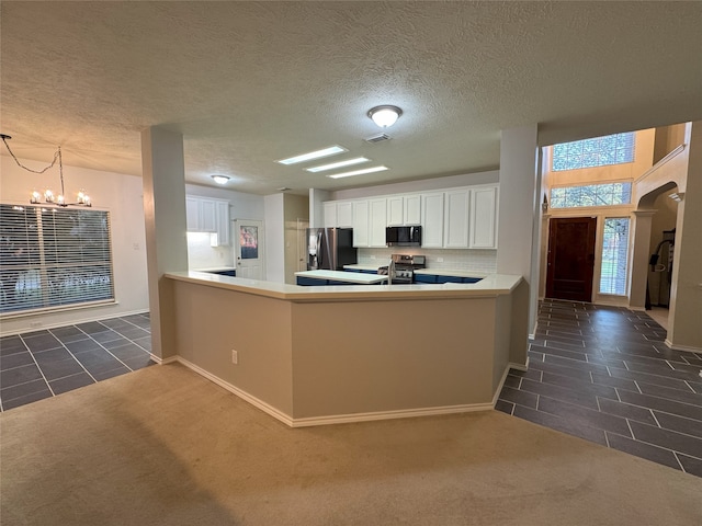 2406 Meadow Tree Ln, Spring, TX 77388 - kitchen featuring stainless steel appliances, a chandelier, dark tile patterned flooring, white cabinets, and a peninsula
