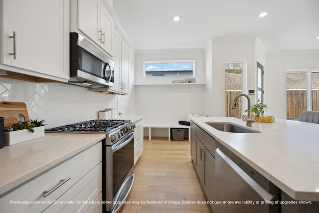 1816 Colquitt St, Houston, TX 77098 - kitchen with appliances with stainless steel finishes, a sink, ornamental molding, light wood-type flooring, and backsplash