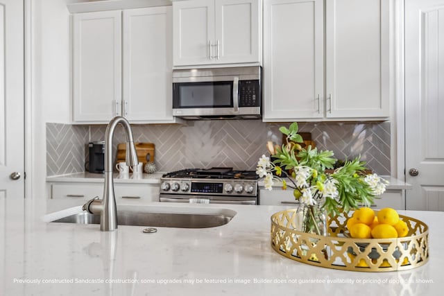 1816 Colquitt St, Houston, TX 77098 - kitchen with stainless steel appliances, a sink, white cabinets, tasteful backsplash, and light stone countertops