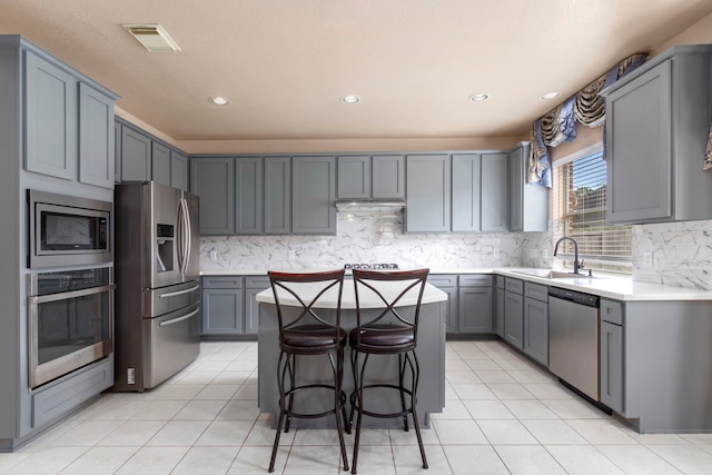 3915 Garnet Fls, Sugar Land, TX 77479 - kitchen featuring stainless steel appliances, a sink, a center island, gray cabinets, and recessed lighting
