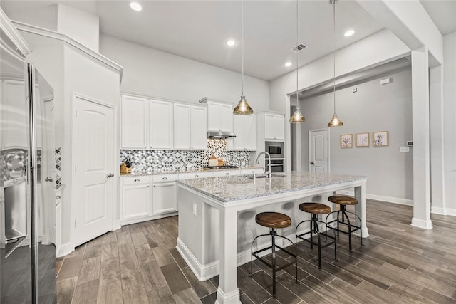 18810 Peachleaf Willow Trce, Cypress, TX 77429 - kitchen featuring appliances with stainless steel finishes, under cabinet range hood, dark wood-type flooring, white cabinetry, and recessed lighting