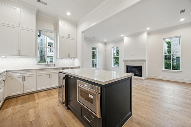 213 Sutton Row Pl, Houston, TX 77024 - kitchen with white cabinets, light wood finished floors, crown molding, wine cooler, and decorative backsplash