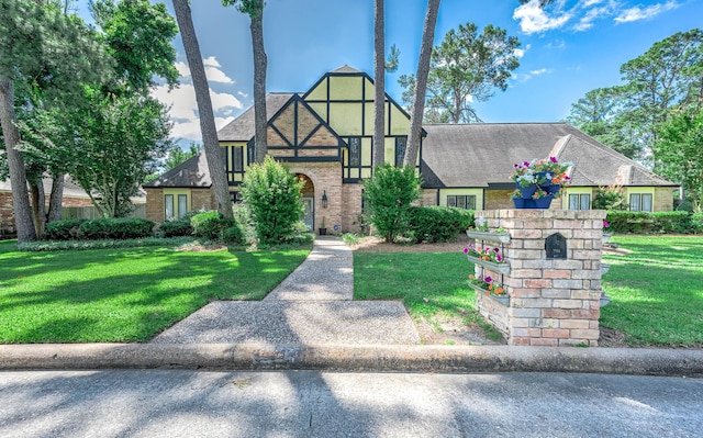 9911 Oxted Ln, Spring, TX 77379 - tudor home featuring brick siding, a front yard, and stucco siding