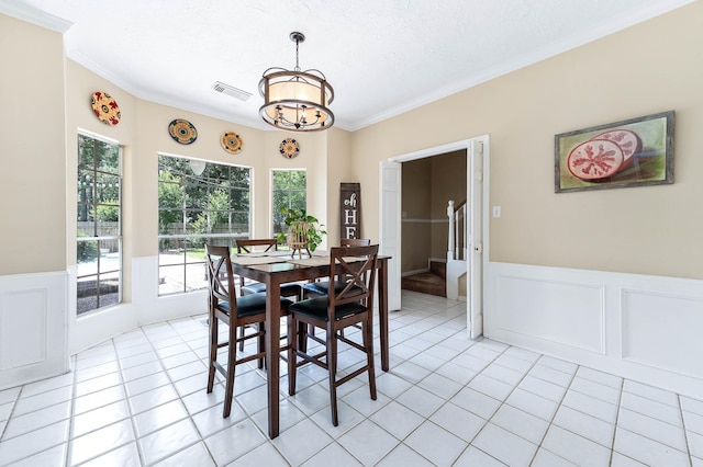 9911 Oxted Ln, Spring, TX 77379 - dining room with crown molding, a chandelier, light tile patterned flooring, a wainscoted wall, and a decorative wall
