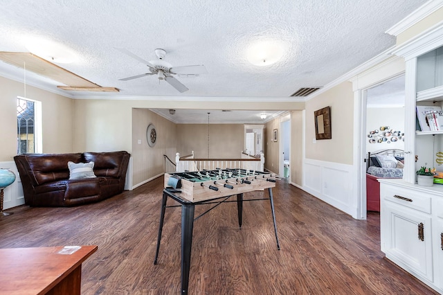9911 Oxted Ln, Spring, TX 77379 - recreation room with dark wood finished floors, a ceiling fan, a textured ceiling, crown molding, and a decorative wall