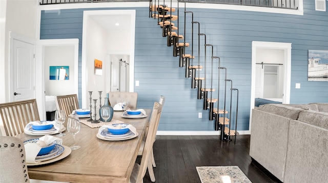 1066 Shady Ln, Gilchrist, TX 77650 - dining space featuring dark wood-style floors, wood walls, stairway, and a barn door
