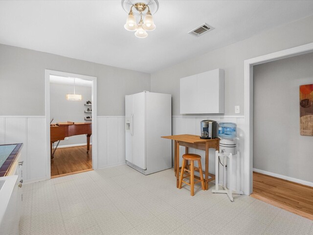 110 Marshall St, League City, TX 77573 - kitchen with white fridge with ice dispenser, a desk, wainscoting, white cabinets, and light wood-style floors