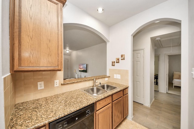 12943 Palm Leaf Ct, Houston, TX 77044 - kitchen featuring a sink, black dishwasher, backsplash, light stone counters, and light wood finished floors
