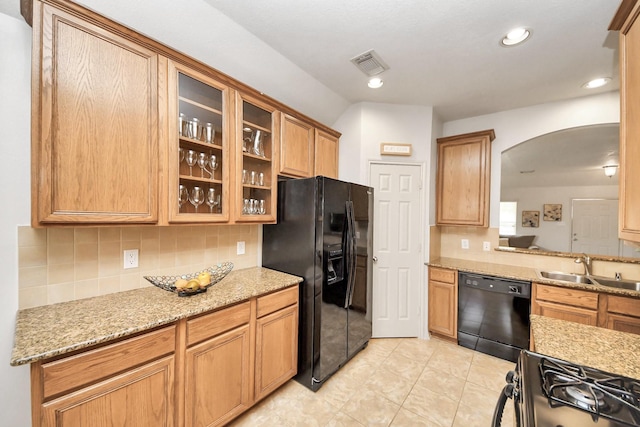 12943 Palm Leaf Ct, Houston, TX 77044 - kitchen with black appliances, a sink, arched walkways, backsplash, and glass insert cabinets