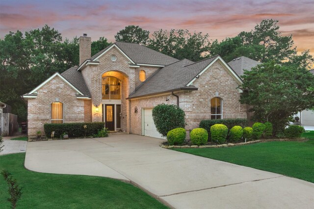 167 Monterrey Rd E, Montgomery, TX 77356 - view of front facade featuring brick siding, a chimney, driveway, an attached garage, and a lawn