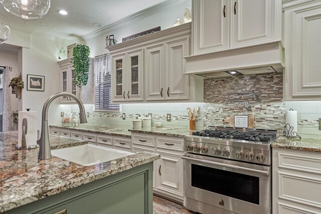 167 Monterrey Rd E, Montgomery, TX 77356 - kitchen featuring high end stainless steel range, a sink, tasteful backsplash, glass insert cabinets, and light stone countertops