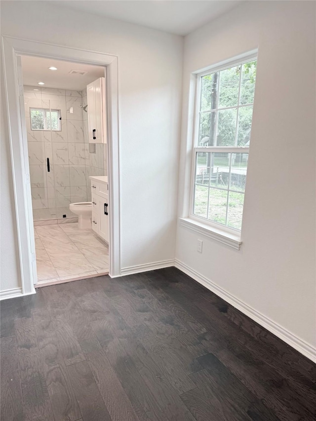 115 Penick Rd, Waller, TX 77484 - unfurnished bedroom featuring multiple windows, wood finished floors, and connected bathroom