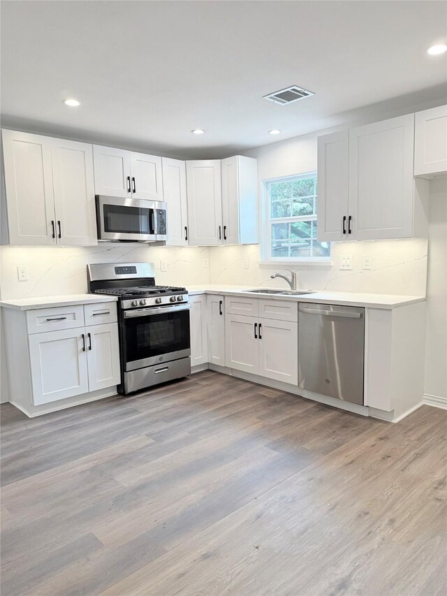 115 Penick Rd, Waller, TX 77484 - kitchen featuring stainless steel appliances, backsplash, white cabinetry, a sink, and light countertops