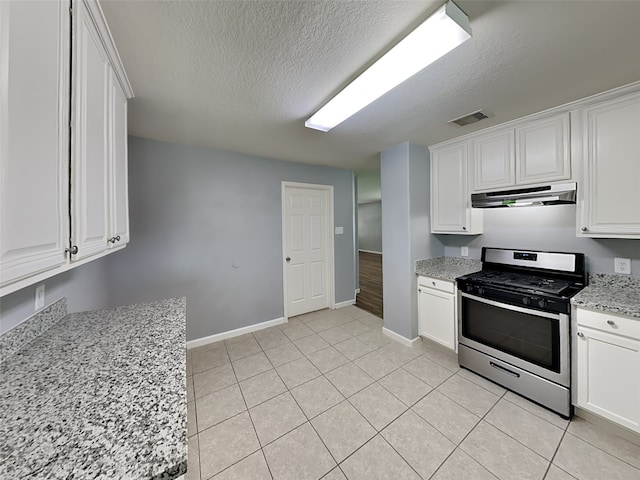 422 Magnolia Way, League City, TX 77573 - kitchen featuring stainless steel range with gas stovetop, under cabinet range hood, baseboards, white cabinetry, and a textured ceiling