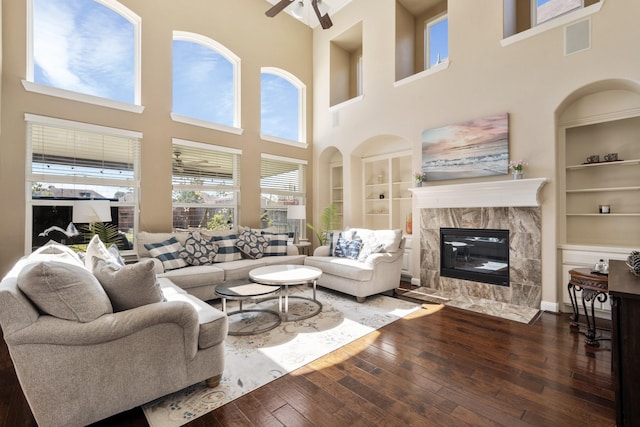 25611 Kearsley Dr, Katy, TX 77494 - living room featuring built in features, wood-type flooring, a high ceiling, a high end fireplace, and a ceiling fan