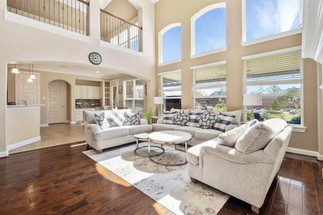 25611 Kearsley Dr, Katy, TX 77494 - living room with arched walkways, dark wood-style flooring, baseboards, and a high ceiling