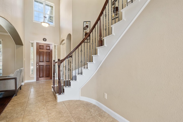 25611 Kearsley Dr, Katy, TX 77494 - entryway with arched walkways, a high ceiling, baseboards, stairway, and tile patterned flooring