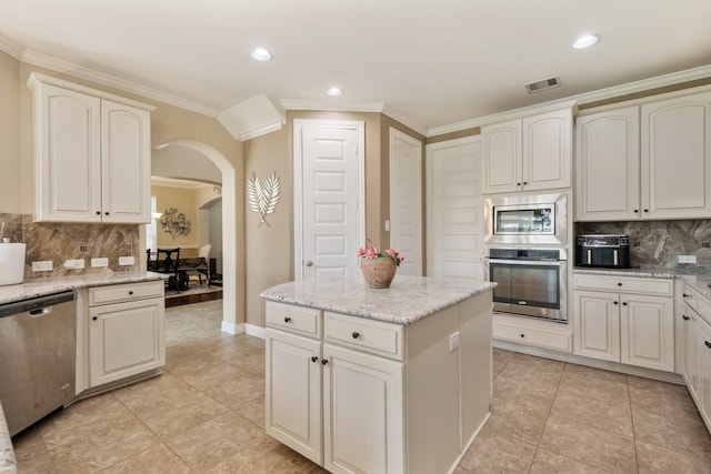25611 Kearsley Dr, Katy, TX 77494 - kitchen with appliances with stainless steel finishes, arched walkways, crown molding, backsplash, and a kitchen island