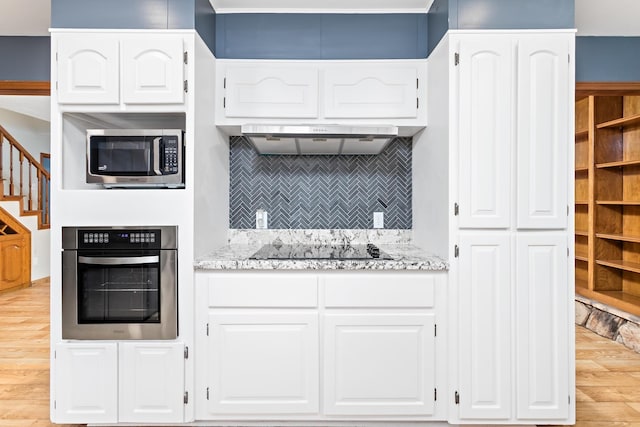 11161 Blue Bonnet Ln, Beaumont, TX 77705 - kitchen with appliances with stainless steel finishes, exhaust hood, light wood-style flooring, white cabinetry, and backsplash