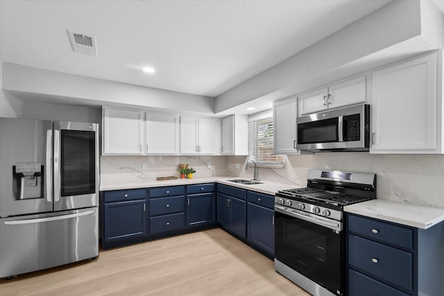 607 Mary Ann Dr, Friendswood, TX 77546 - kitchen with appliances with stainless steel finishes, blue cabinets, white cabinets, a sink, and light wood-style floors