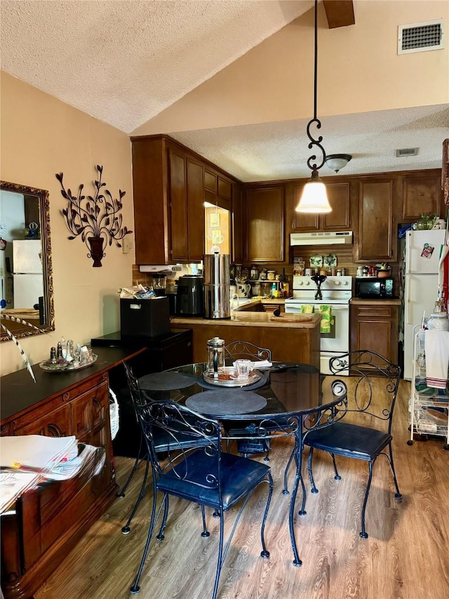 1347 Cardinal Ln, Trinity, TX 75862 - kitchen with white appliances, vaulted ceiling, under cabinet range hood, wood finished floors, and a textured ceiling
