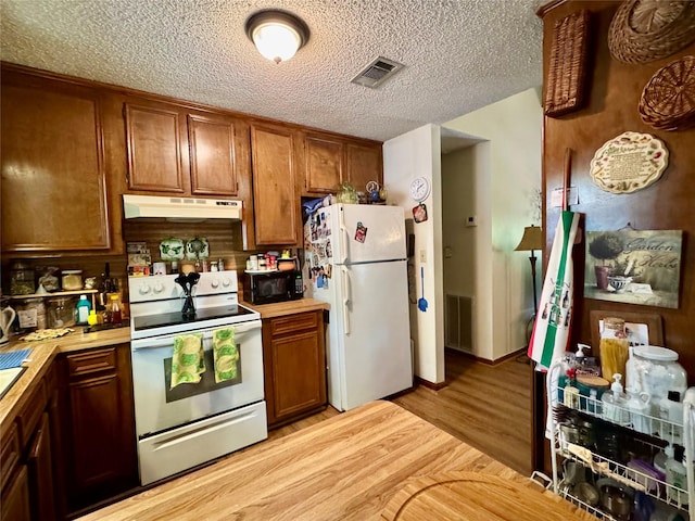 1347 Cardinal Ln, Trinity, TX 75862 - kitchen featuring white appliances, under cabinet range hood, light countertops, light wood-style floors, and brown cabinetry
