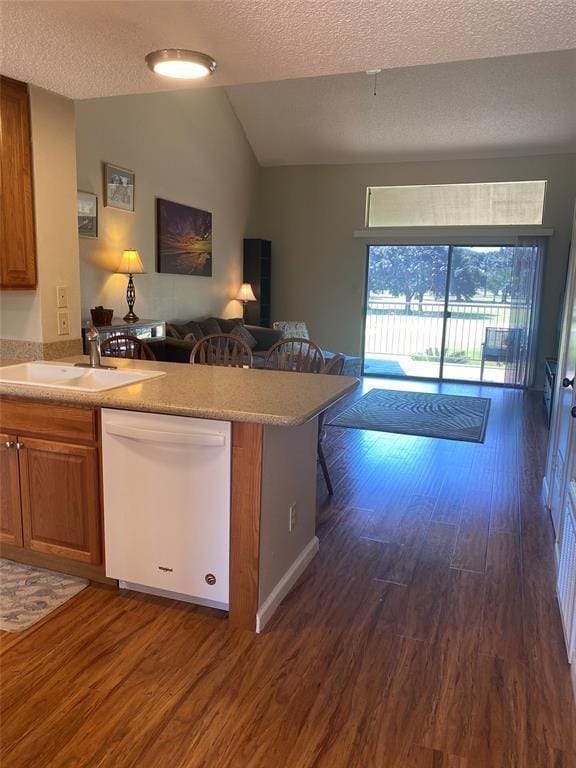 8435 Sands Point Dr, Houston, TX 77036 - kitchen with white dishwasher, a sink, brown cabinetry, dark wood-style flooring, and vaulted ceiling