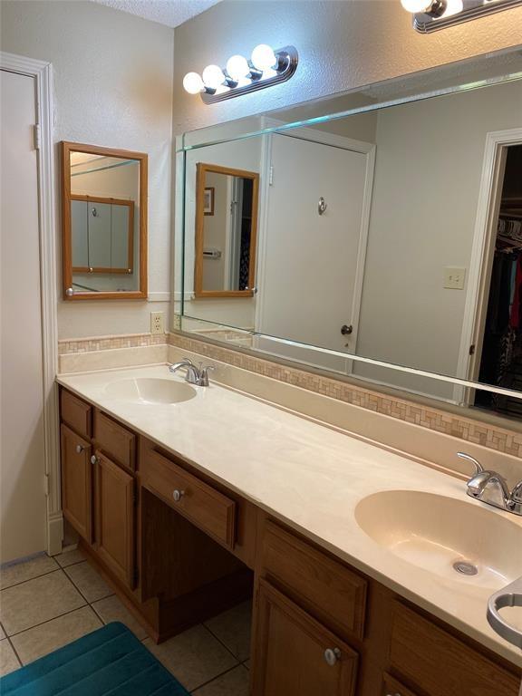 8435 Sands Point Dr, Houston, TX 77036 - full bath with tile patterned floors, double vanity, and a spacious closet