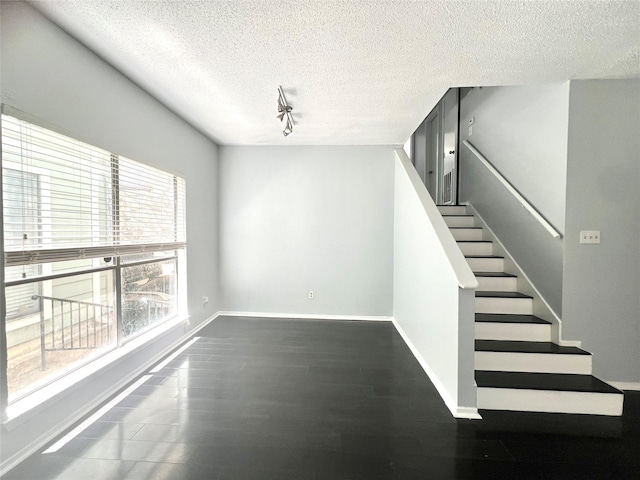 3754 Tanglewilde St Unit 9, Houston, TX 77063 - stairs with a textured ceiling, rail lighting, baseboards, and wood finished floors
