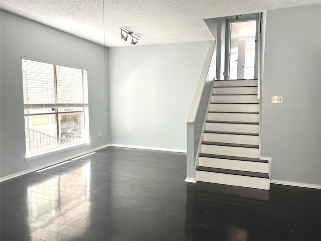 3754 Tanglewilde St Unit 9, Houston, TX 77063 - staircase with a textured ceiling, baseboards, track lighting, and wood finished floors