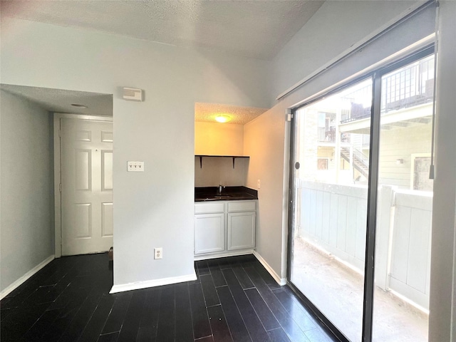 3754 Tanglewilde St Unit 9, Houston, TX 77063 - kitchen with dark wood-style flooring, a sink, baseboards, white cabinetry, and dark countertops