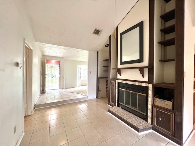 4306 Rosebud Dr, Houston, TX 77053 - unfurnished living room with light tile patterned flooring, a glass covered fireplace, a textured ceiling, and baseboards