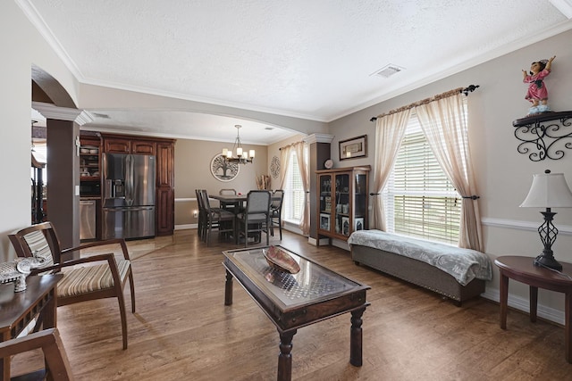2218 Cherry Ln, Pasadena, TX 77502 - living area with arched walkways, decorative columns, a textured ceiling, light wood finished floors, and crown molding