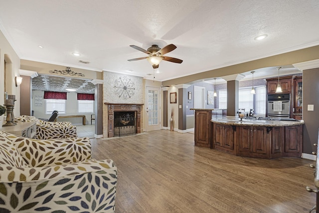 2218 Cherry Ln, Pasadena, TX 77502 - living room featuring ceiling fan, light wood-type flooring, a large fireplace, healthy amount of natural light, and ornamental molding
