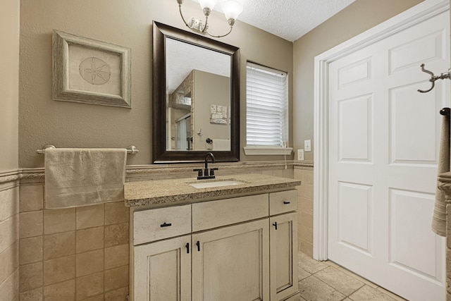 2218 Cherry Ln, Pasadena, TX 77502 - bathroom featuring vanity, tile walls, wainscoting, a textured ceiling, and tile patterned floors