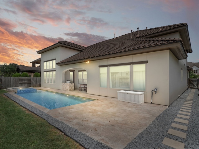 6407 Caparra Rock Ln, Sugar Land, TX 77479 - back of property at dusk with a tile roof, a fenced backyard, stucco siding, and a patio