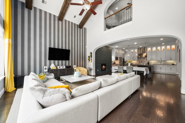 6407 Caparra Rock Ln, Sugar Land, TX 77479 - living room featuring a ceiling fan, arched walkways, dark wood-style flooring, a high ceiling, and beamed ceiling