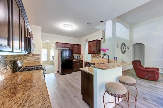 10531 Sunflower Dr, Willis, TX 77318 - kitchen featuring appliances with stainless steel finishes, arched walkways, a kitchen breakfast bar, light wood finished floors, and a sink