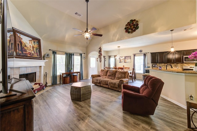 10531 Sunflower Dr, Willis, TX 77318 - living area with high vaulted ceiling, a ceiling fan, a fireplace, dark wood finished floors, and arched walkways