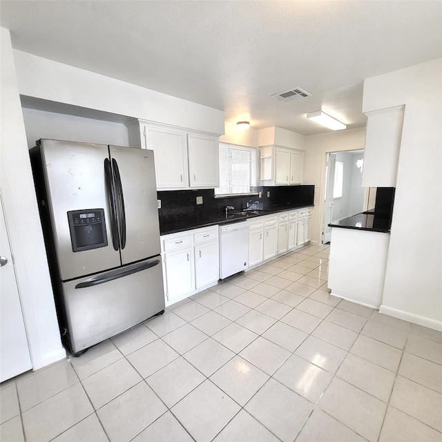 17223 Artwood Ln, Houston, TX 77489 - kitchen with stainless steel fridge, dishwasher, dark countertops, light tile patterned floors, and white cabinetry