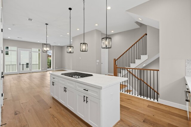 1139 W 22nd St, Houston, TX 77008 - kitchen with stainless steel gas stovetop, light wood-type flooring, white cabinetry, recessed lighting, and hanging light fixtures