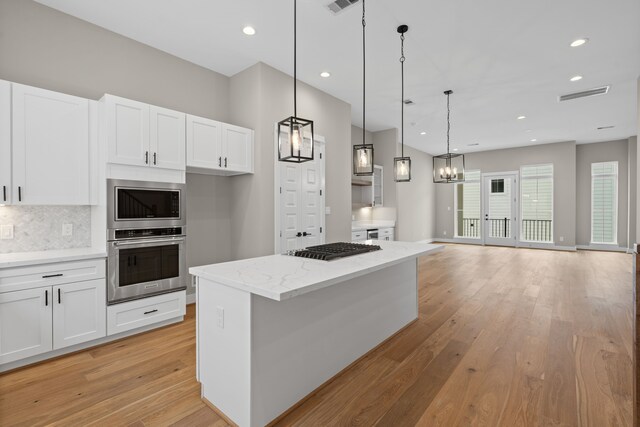 1139 W 22nd St, Houston, TX 77008 - kitchen with appliances with stainless steel finishes, white cabinets, light wood-style flooring, tasteful backsplash, and recessed lighting