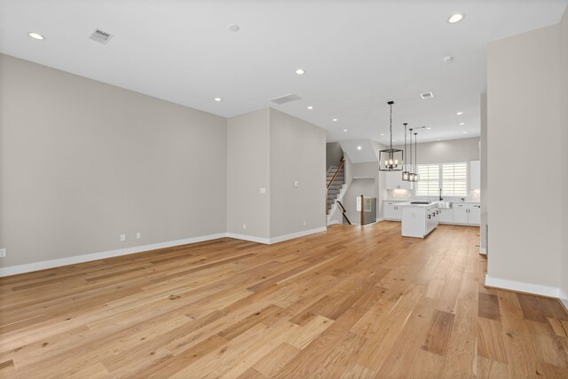 1139 W 22nd St, Houston, TX 77008 - unfurnished living room with light wood-type flooring, stairs, recessed lighting, and baseboards