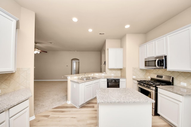 7315 Palmito Ranch Dr, Richmond, TX 77406 - kitchen with stainless steel appliances, a peninsula, a sink, white cabinetry, and recessed lighting