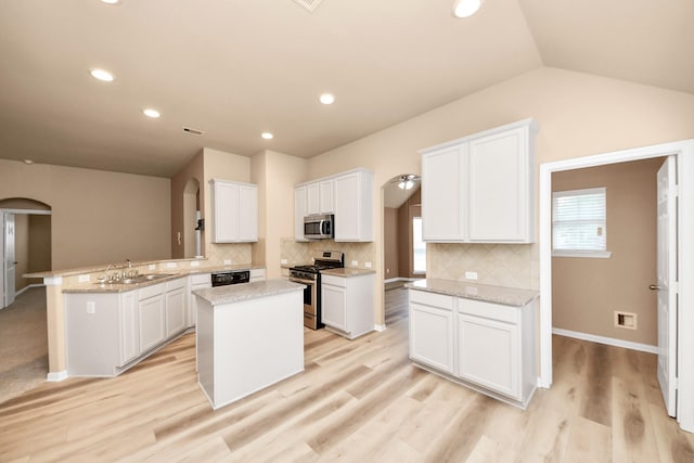 7315 Palmito Ranch Dr, Richmond, TX 77406 - kitchen with appliances with stainless steel finishes, a sink, arched walkways, a peninsula, and white cabinetry